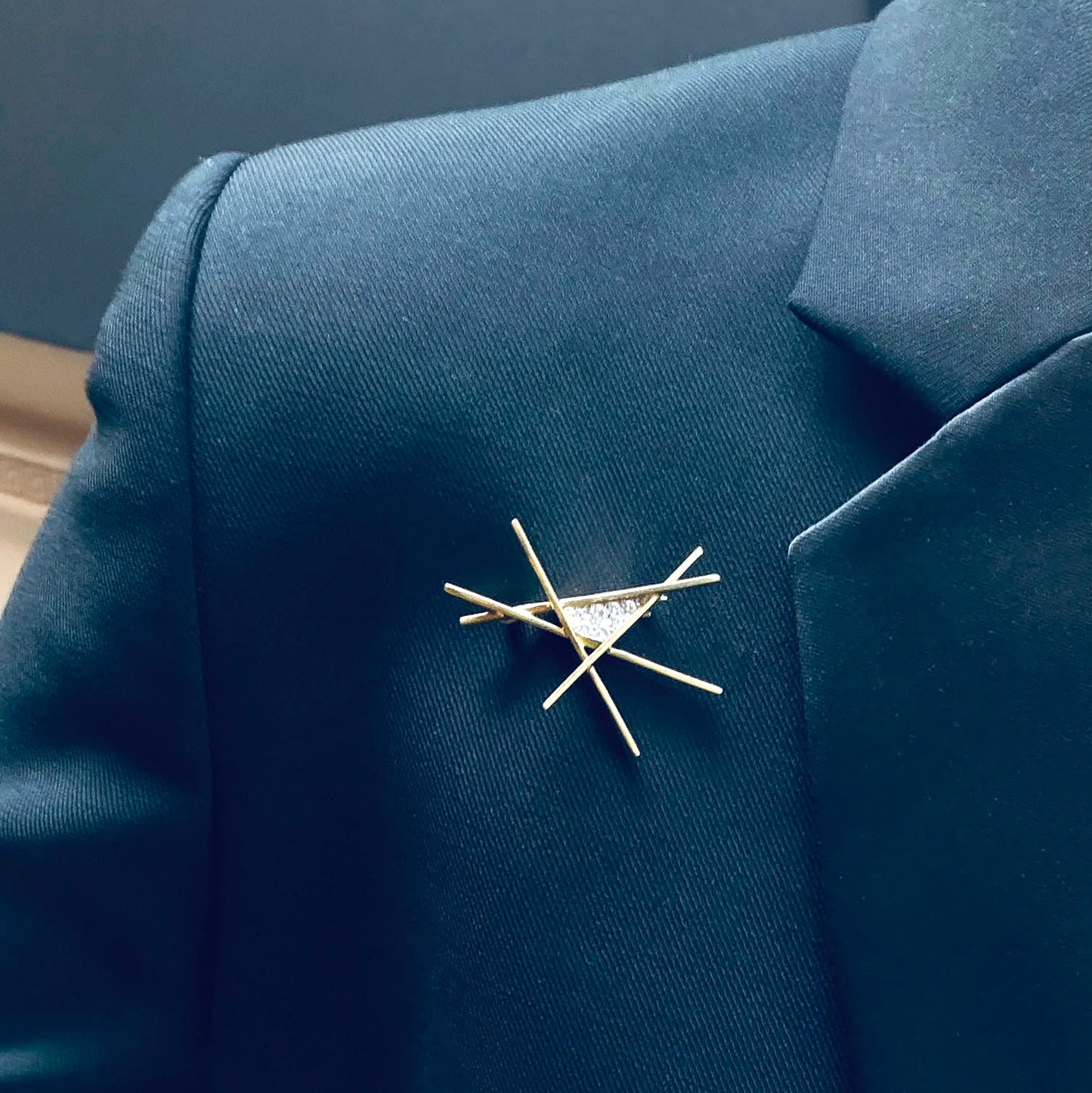 Gold brooch on a blue blazer against a neutral background